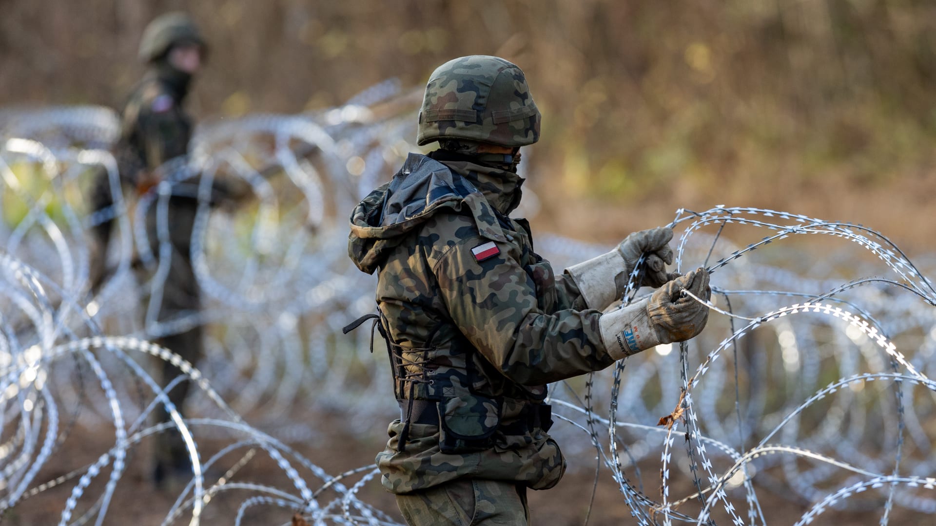 جنديان من الجيش البولندي يضعان أسلاكا شائكة على الحدود مع روسيا