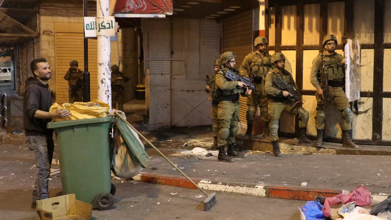 صورة تظهر عناصر أمن إسرائيلي إلى جانب عامل نظافة فلسطيني في القدس خلال المواجهات 