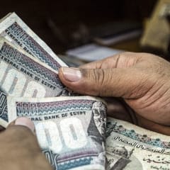 صورة أرشيفية لرجل يعد جنيهات مصرية