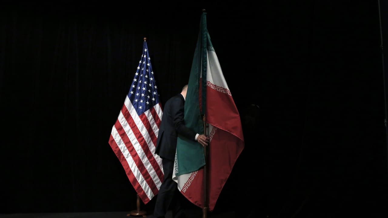 موظف يرفع العلم الإيراني بعد صورة جماعية خلال المحادثات النووية في فيينا عام 2015 