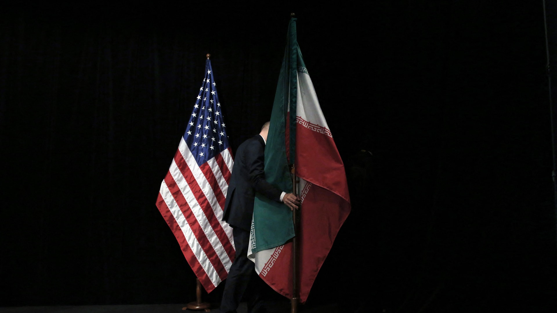 موظف يرفع العلم الإيراني بعد صورة جماعية خلال المحادثات النووية في فيينا عام 2015 