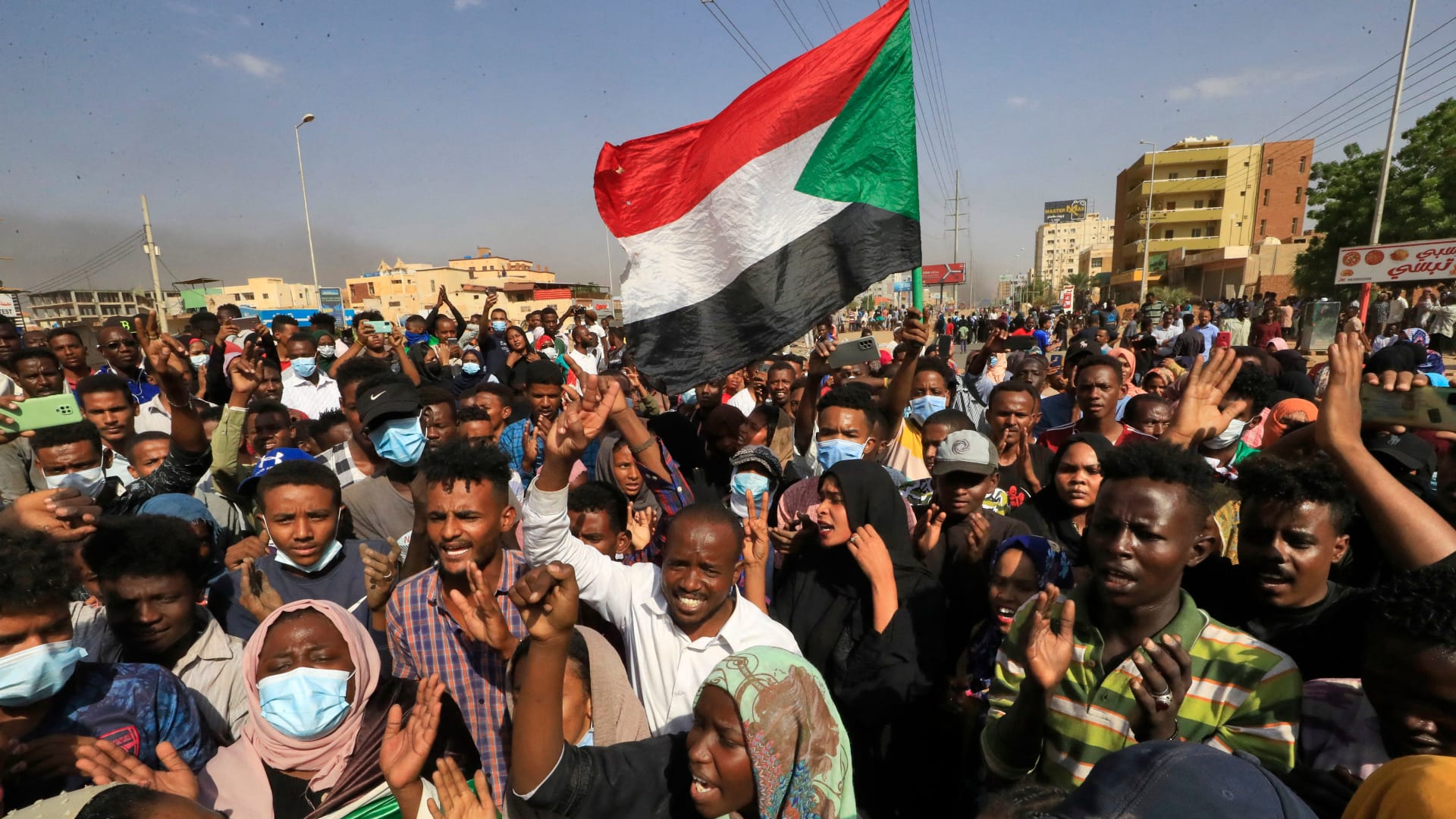 متظاهرون سودانيون يرفعون الأعلام الوطنية أثناء تجمعهم في شارع الستين بالعاصمة الخرطوم للتنديد باعتقالات الجيش لأعضاء الحكومة في 25 أكتوبر/ تشرين الأول 2021.