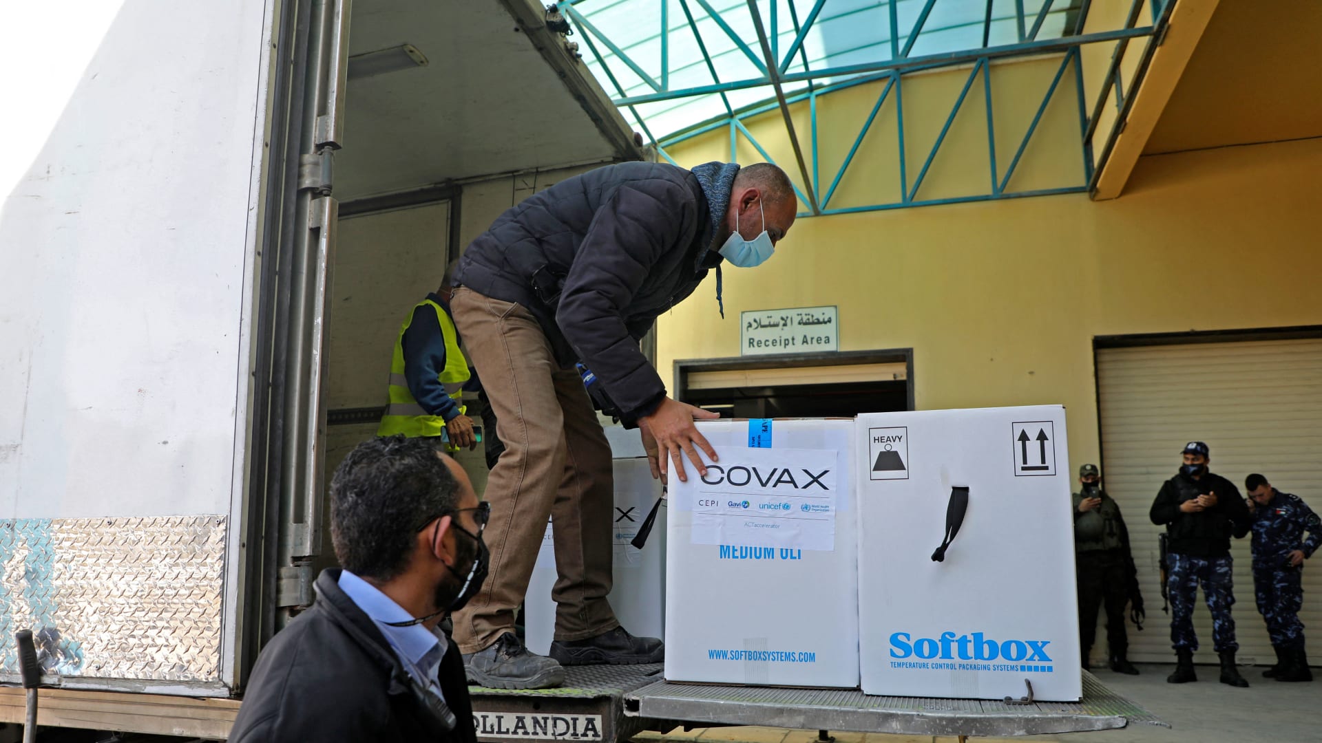 عامل يفرغ شاحنة مبردة تحمل أول شحنة من لقاح كورونا عبر برنامج Covax التابع للأمم المتحدة، في مدينة نابلس بالضفة الغربية ، 17 مارس 2021