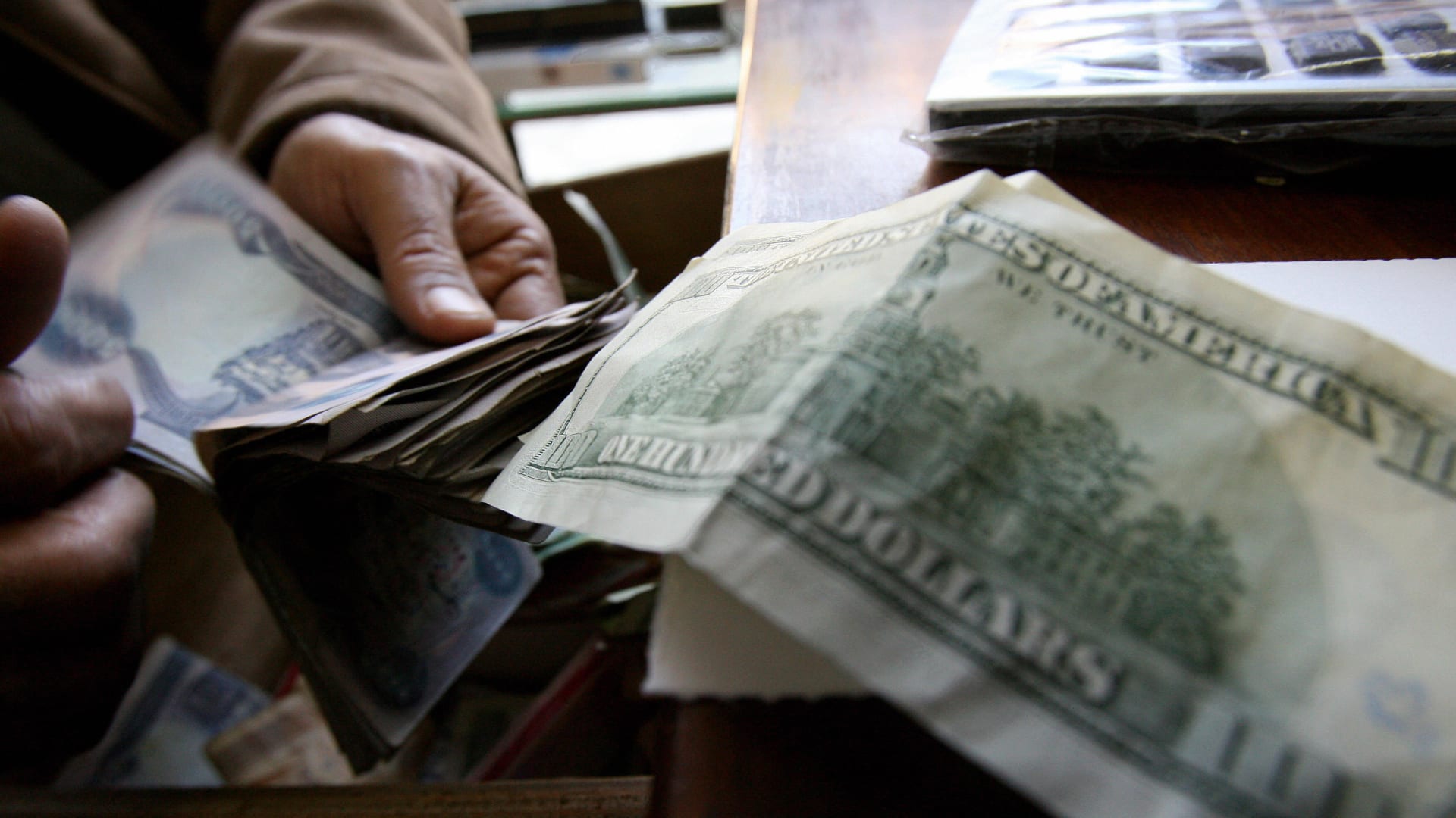 صورة أرشيفية العام 2007 لرجل يعد نقودا عراقية أمام ورقة 100 دولار 