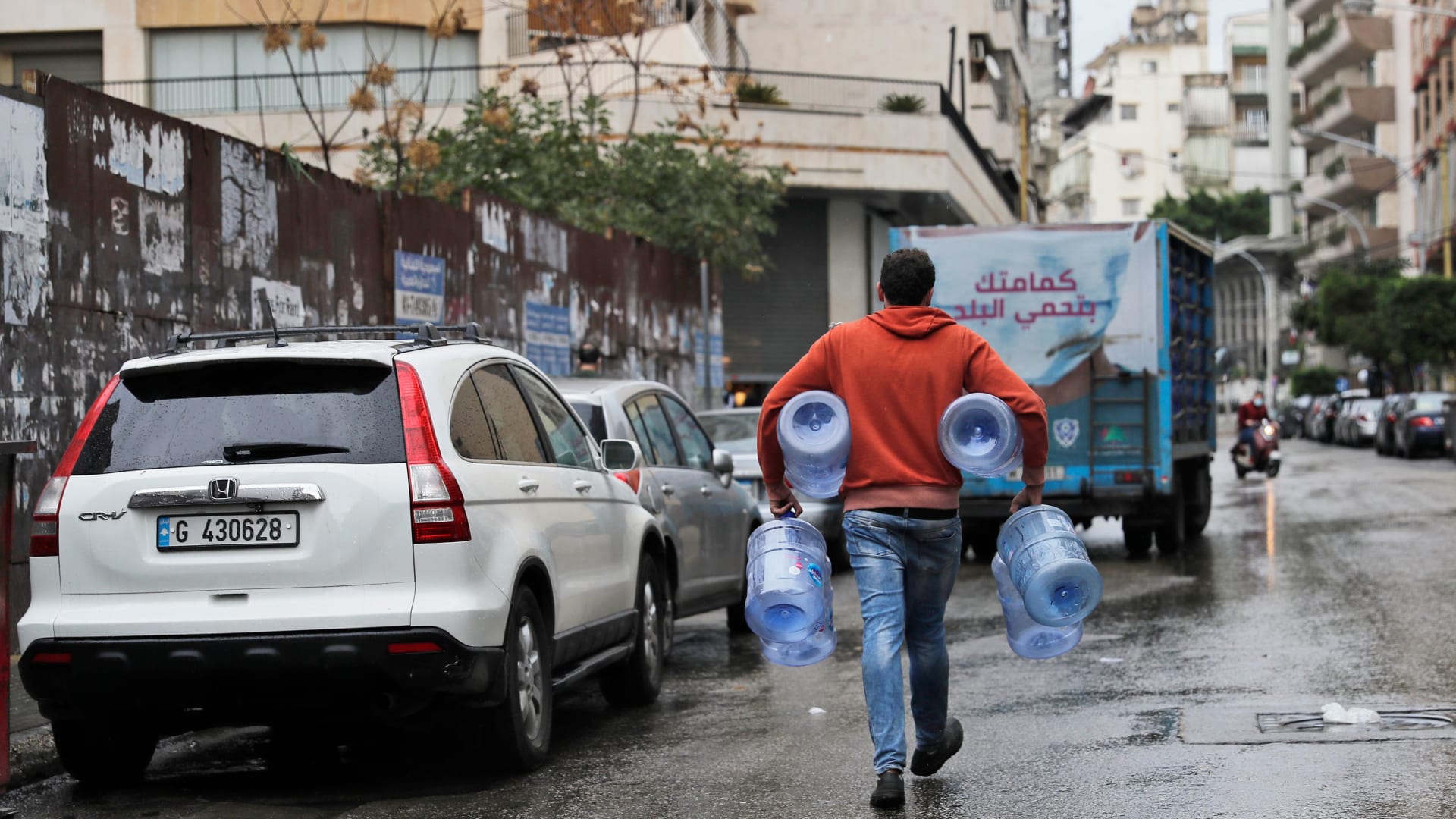 شاب يسير مع جالون ماء فارغ في شارع شبه مهجور في العاصمة بيروت، حيث يدخل لبنان يومه الأول من الإغلاق الصارم الذي فرضته السلطات في محاولة لوقف انتشار فيروس كورونا، في 14 كانون الثاني (يناير) 2021