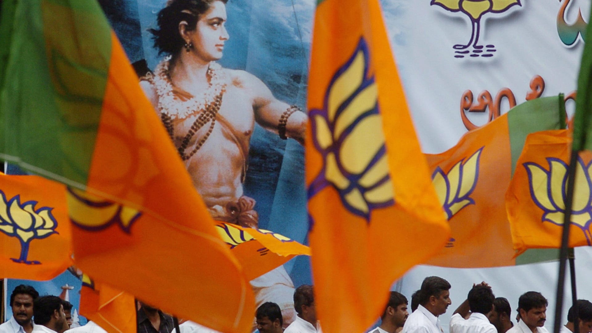 صورة ارشيفية لمؤيدين لحزب بهارتا يرفعون أعلام الحزب مع صورة في الخلفية لأحد الآلة الهندوسية
