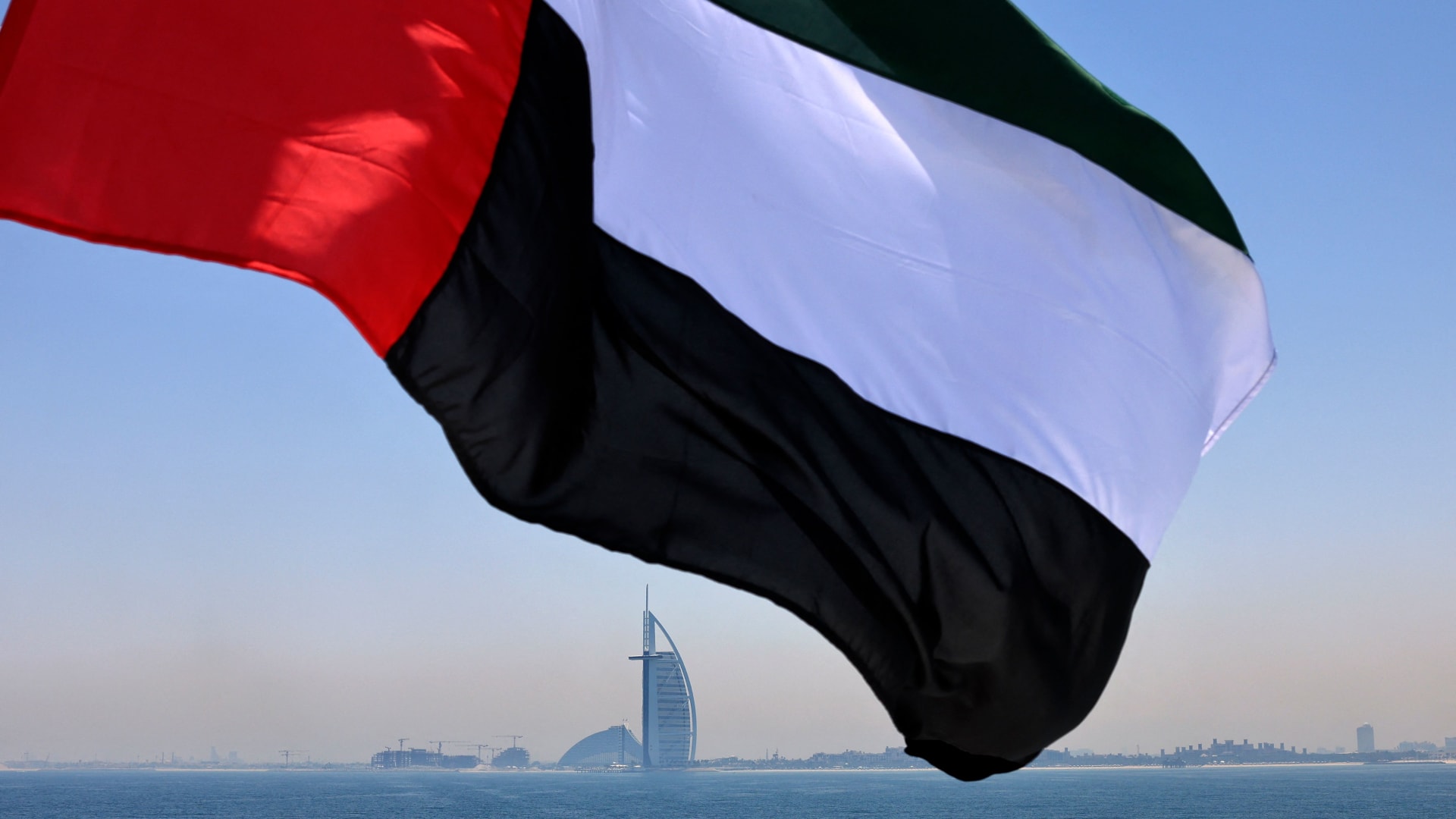 علمًا إماراتيًا يرفرف فوق مرسى دبي مع فندق برج العرب في الخلفية