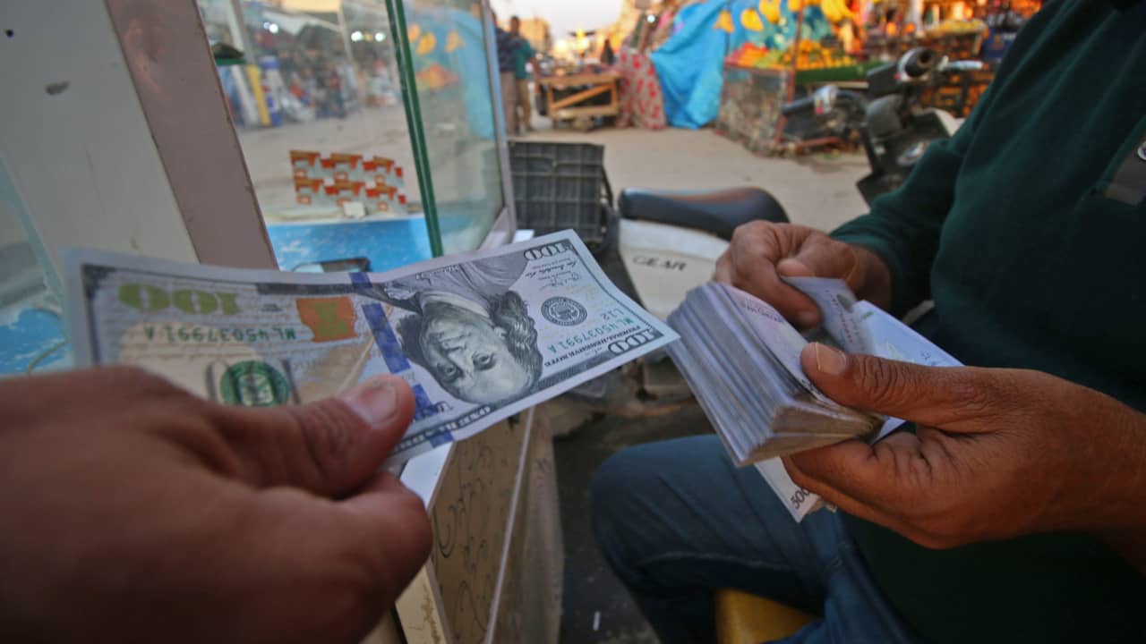 صورة أرشيفية لرجل عراقي يغير الدولار مقابل الريال الإيراني في البصرة