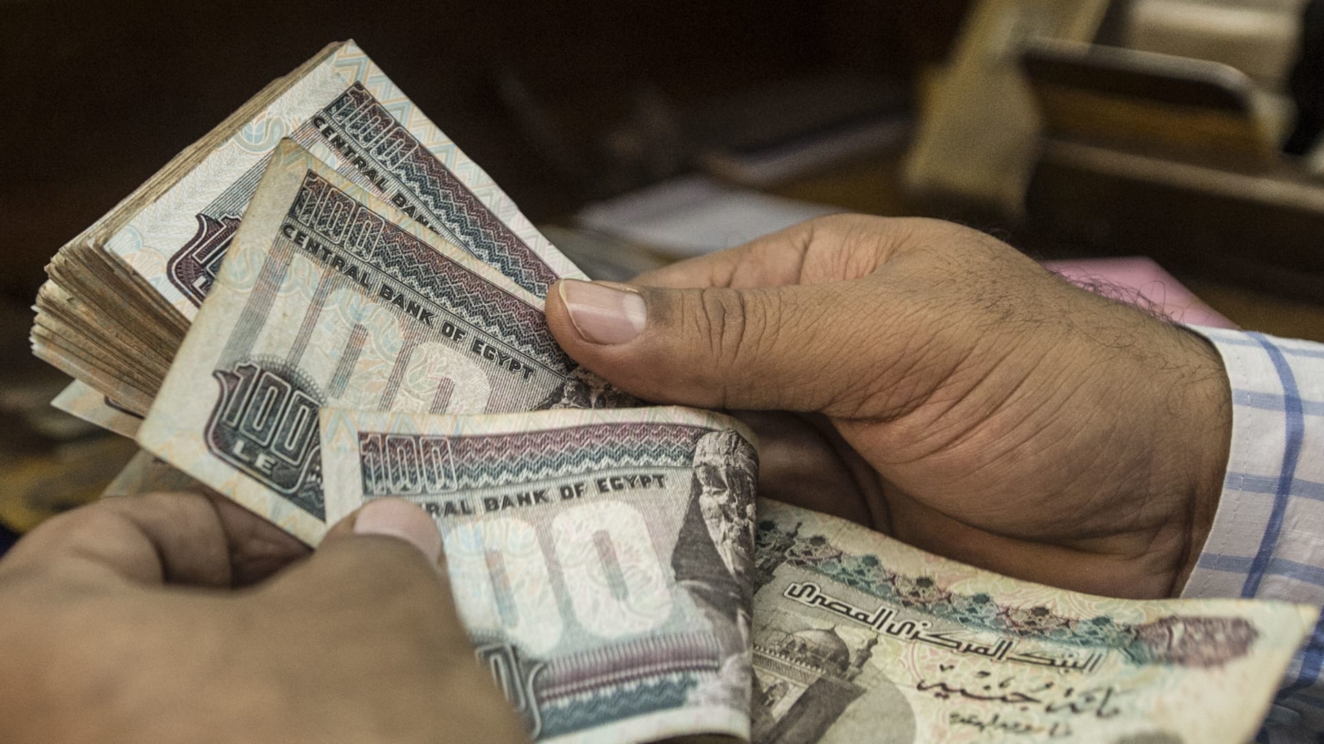 رجل يعد جنيهات مصرية في محل صرافة بالقاهرة