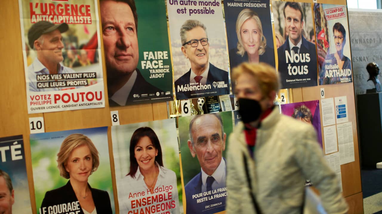 امرأة تسير أمام ملصقات لمرشحين بالانتخابات الفرنسية 